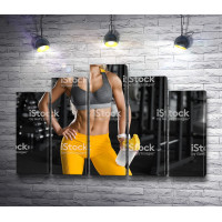 Девушка в желтых лосинах в фитнес зале 
