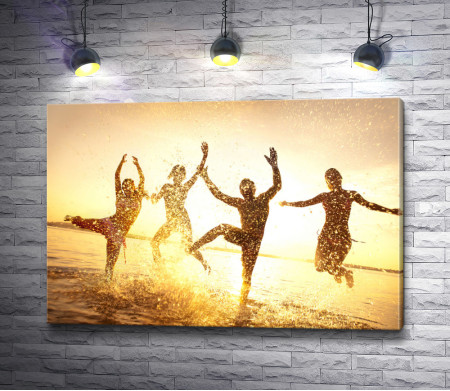 Люди танцуют на берегу моря во время заката