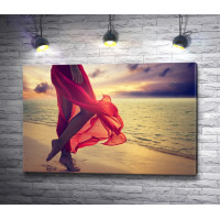 Ноги девушки в шелковой красной юбке на пляже 