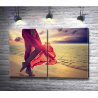 Ноги девушки в шелковой красной юбке на пляже 