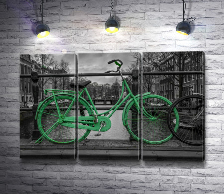 Зеленый велосипед на мосту на фоне черно-белого города