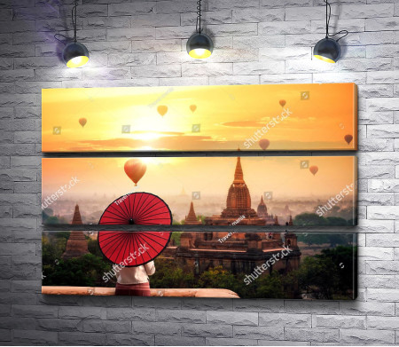 Девушка с красным зонтом смотрит на город в лучах заката